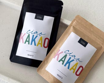 Könnte beinhalten: Zwei versiegelte Beutel, einer schwarz und einer braun, mit weißen Etiketten. Auf den Etiketten steht "ciao KAKAO" in bunten Buchstaben. Der schwarze Beutel hat ein "Schoki"-Etikett. Der braune Beutel hat ein "Schoki"-Etikett. Der Text "FRÄULEINZ" IN steht unten auf den Etiketten.