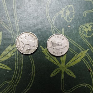 May include: Two silver Irish coins on a green background. The first coin features a hare and the text "IRELAND" and "3d". The second coin features a harp and the text "EIRE" and "1946".