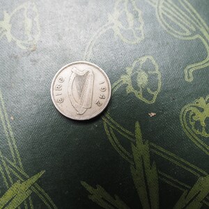 May include: A silver Irish coin with the year 1942 and the word "EIRE" inscribed around the edge. The coin features a harp in the center.