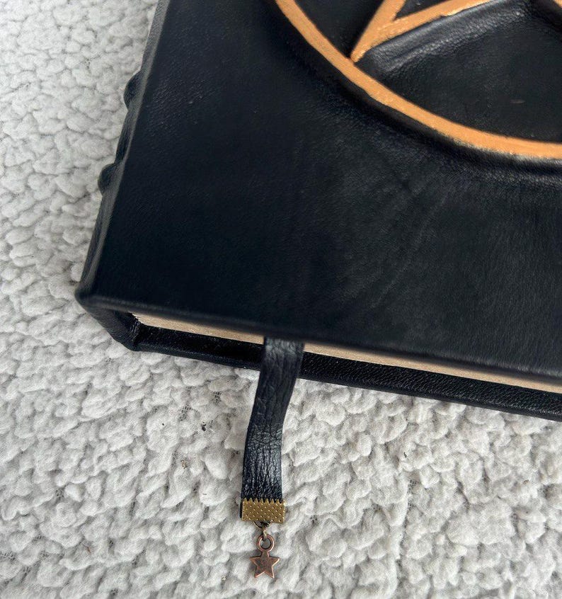 May include: Black leather journal with a gold pentagram design and a gold tassel bookmark.