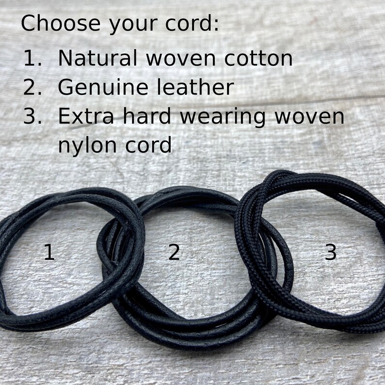 May include: Three different types of cord for jewellery making: natural woven cotton, genuine leather, and extra hard wearing woven nylon cord. The cords are black and are shown coiled on a wooden surface.