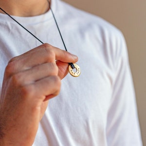 May include: A gold necklace with a round pendant that has the text "1989" engraved on it.
