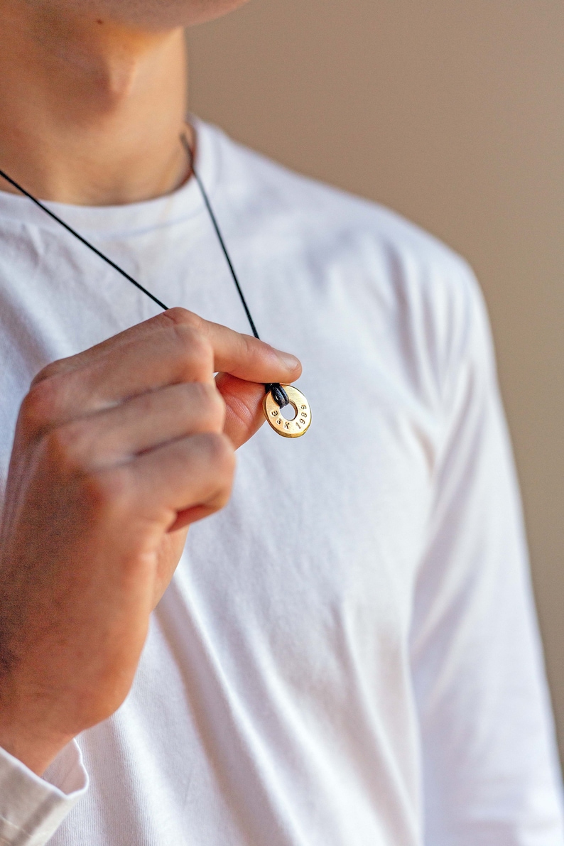 May include: A gold necklace with a round pendant that has the text "1989" engraved on it.