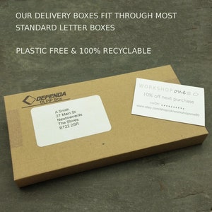 May include: A brown cardboard box with the text "OUR DELIVERY BOXES FIT THROUGH MOST STANDARD LETTER BOXES PLASTIC FREE & 100% RECYCLABLE" printed on the top. The box has a white label with the text "DEFENDA DL PIP Box A Smith 27 Main St Newtownards The Shires BT22 2SR" printed on it. A white card with the text "WORKSHOP one80 10% off next purchase code:... www.etsy.com/shop/uk/workshopone80" is on top of the box.