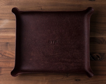 May include: A burgundy leather catchall tray with the letters "BTP" embossed in the center.