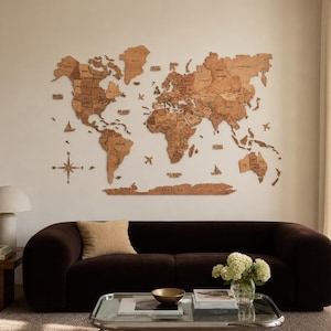 May include: A large, multi-piece wooden world map wall art installation featuring laser-cut continents, countries, and ocean names. The map includes decorative wooden icons of airplanes, ships, and a compass rose, all mounted directly onto the wall.