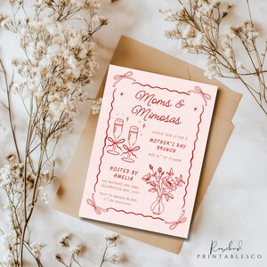 May include: Pink invitation card with red text and illustrations. The text reads "Moms & Mimosas" and "Please join us for a Mother's Day Brunch, May 12th at 11:00am". The illustration includes two champagne glasses with bows and a vase with flowers.