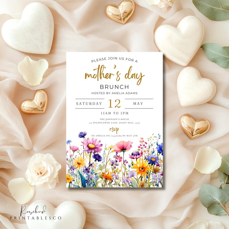 May include: A white invitation card with a floral design and gold lettering. The text reads "Please join us for a mother's day brunch hosted by Amelia Adams Saturday 12 May 11am to 1pm The Johnson's House Wildflower Lane, Daisy Hill RSVP to Amelia on by May 12th".