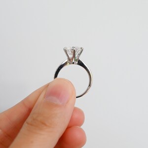K&ouml;nnte beinhalten: Ein silberner Ring mit einem gro&szlig;en, klaren, runden Diamanten.