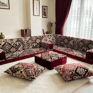 Puede incluir: Un juego de sala de estar con un gran sofá esquinero, una otomana y dos cojines. Los muebles tienen una base burdeos con un diseño estampado en crema, marrón y verde. Los cojines son cuadrados y tienen un patrón similar.