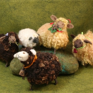May include: A collection of six handcrafted sheep figurines. The sheep are made of wool and have various colors, including brown, white, and tan. Some sheep have decorative accessories like bells, ribbons, and greenery. The figurines are arranged on a green surface.