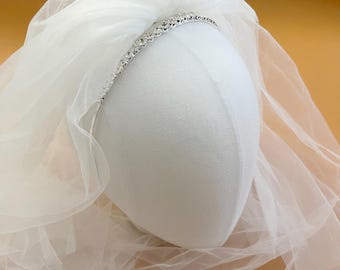 May include: White bridal veil with a silver headband adorned with rhinestones.