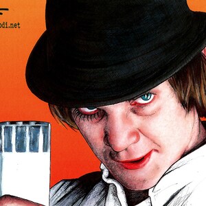 May include: A man wearing a black fedora and a white shirt holds a glass of milk. He has a serious expression on his face and his eyes are piercing.