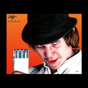 May include: A man wearing a black fedora and a white shirt holds a glass of milk. He has a serious expression on his face and his eyes are looking directly at the viewer. The background is a bright orange colour.
