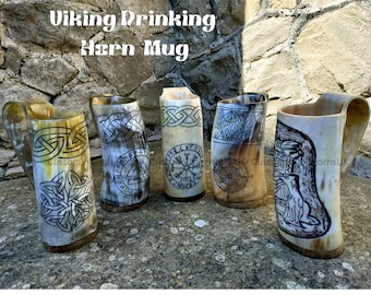 May include: Five intricately carved Viking drinking horn mugs with various designs, including Celtic knots, runes, and a compass. The horns are made of natural materials and have a rustic, handcrafted look.