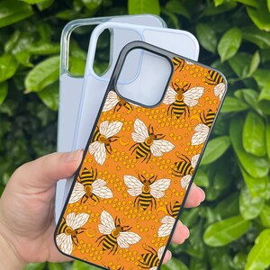May include: A black phone case with a pattern of bees, honeycombs, and moons on an orange background.