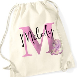 Puede incluir: Una bolsa de cordón blanco con una "M" rosa para Melody y una ilustración de dinosaurio morado.