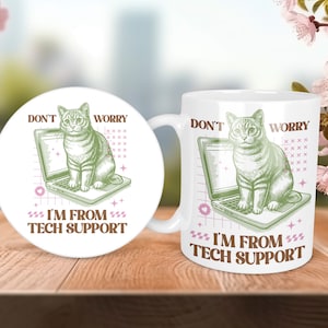 May include: White ceramic mug featuring a green illustration of a cat sitting on a laptop. The text "Don't Worry I'm From Tech Support" is printed on the mug.
