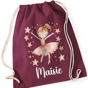 May include: Burgundy drawstring bag with a white personalised name "Maisie" and a watercolour illustration of a ballerina girl with stars.