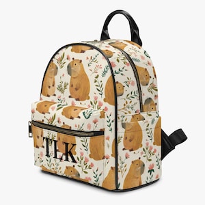 May include: A cream-colored backpack with a floral pattern featuring capybaras. The backpack has black straps and a black zipper. The letters "TLK" are printed in black on the front of the backpack.