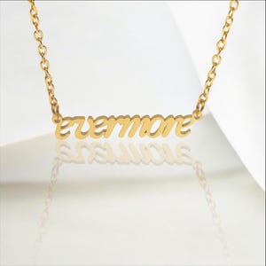May include: A gold necklace with a cursive 'evermore' pendant.