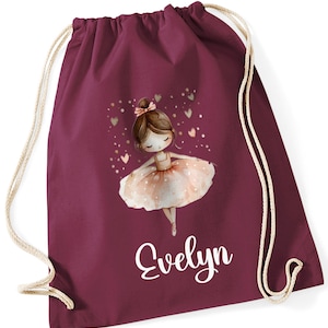May include: Burgundy drawstring bag with a white personalised name "Evelyn" and a pink ballerina illustration with hearts and gold glitter.