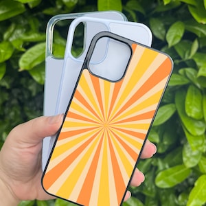 May include: A black phone case with a yellow and orange sunburst design. The case is shown with a clear phone case behind it.