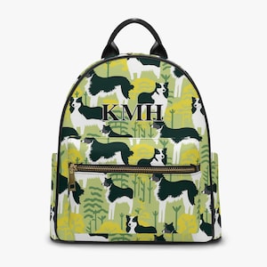 Könnte beinhalten: Rucksack mit schwarzem und weißem Border-Collie-Hundemuster mit grünem und gelbem Laub. Der Rucksack hat einen schwarzen Reißverschluss und einen goldenen Reißverschluss-Zipper. Die Initialen KMH sind auf der Vorderseite des Rucksacks gestickt.
