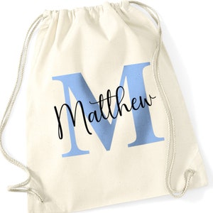 May include: A white drawstring bag with a light blue letter M and the name Matthew written in black cursive.