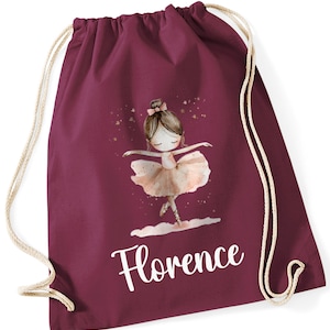 May include: Burgundy drawstring bag with a white personalised name "Florence" and a graphic of a ballerina with a pink tutu and brown hair. The ballerina is surrounded by gold stars.