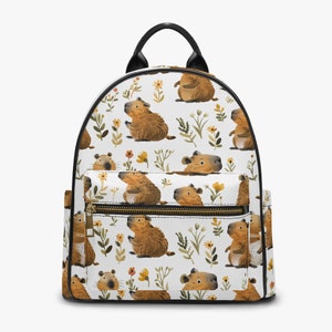 May include: White backpack with a repeating pattern of brown capybaras and green and yellow flowers. The backpack has black straps and a black zipper.