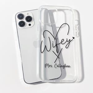 May include: Clear phone case with a black design that says "Wifey" with a heart and an X underneath. The text "Mrs. Callaghan" is below the design.