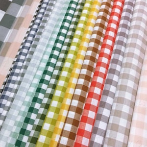 May include: A collection of 14 fabric swatches in various gingham patterns. The swatches are arranged in a rainbow color order, starting with a light green and ending with a light pink. The gingham patterns are all white and a different color, including green, blue, yellow, orange, red, brown, and gray.