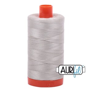 May include: A spool of silver gray thread with an orange plastic bobbin and the text "Aurifil" in blue and white.