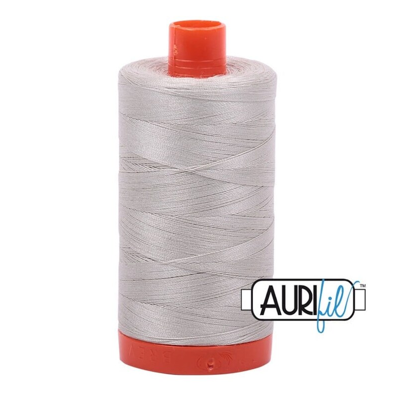 May include: A spool of silver gray thread with an orange plastic bobbin and the text "Aurifil" in blue and white.