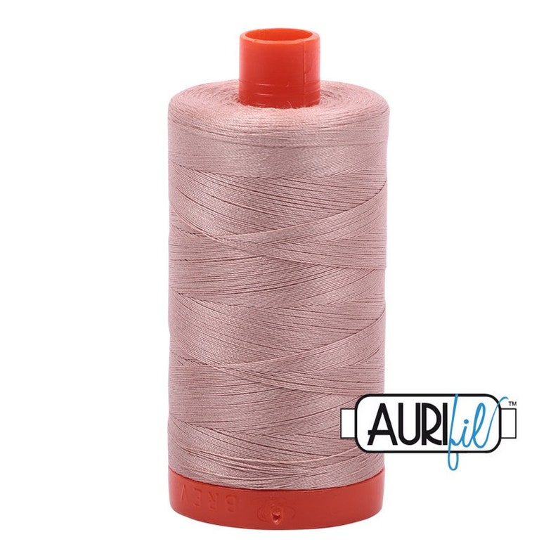 May include: A spool of pale pink thread with a red plastic bobbin and the Aurifil logo in blue.