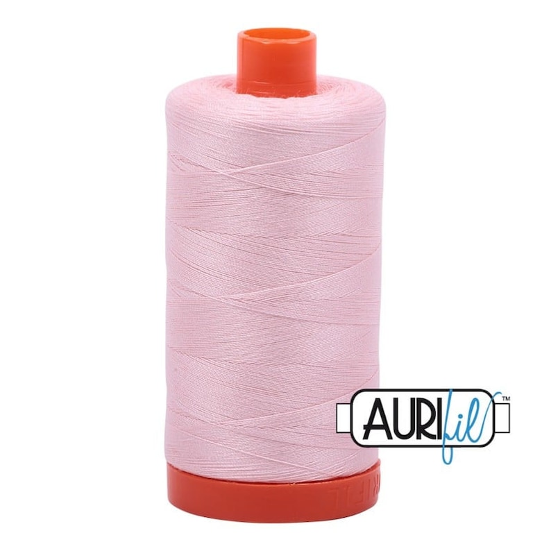 May include: A spool of pink thread with an orange top and bottom. The spool is labeled "Aurifil" in a black rectangle.
