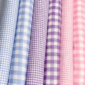 May include: Five rolls of fabric with different colored gingham patterns. The rolls are arranged from left to right: light blue, purple, light purple, pink, and light pink.