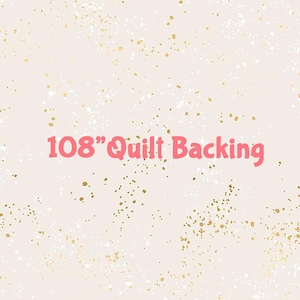 May include: A light pink fabric featuring a scattered pattern of small gold and white speckles. The text 108" Quilt Backing is printed in large, bold, pink letters across the center of the fabric, indicating the width of the material.