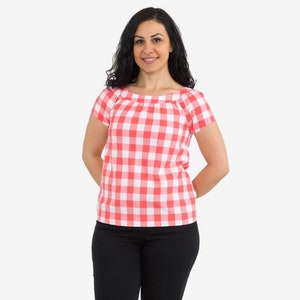 May include: A woman wearing a red and white gingham top with short sleeves and black pants.