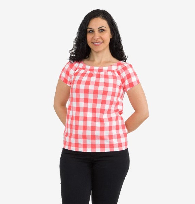 May include: A woman wearing a red and white gingham top with short sleeves and black pants.