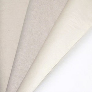 May include: Five different white fabric swatches, arranged in a fan shape, showing the different textures and shades of white.