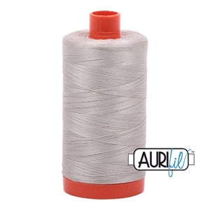 May include: A spool of silver gray thread with an orange plastic bobbin and the text "Aurifil" in blue.