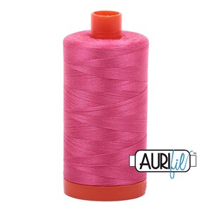 May include: A spool of pink thread with an orange plastic bobbin and the text "Aurifil" on the label.
