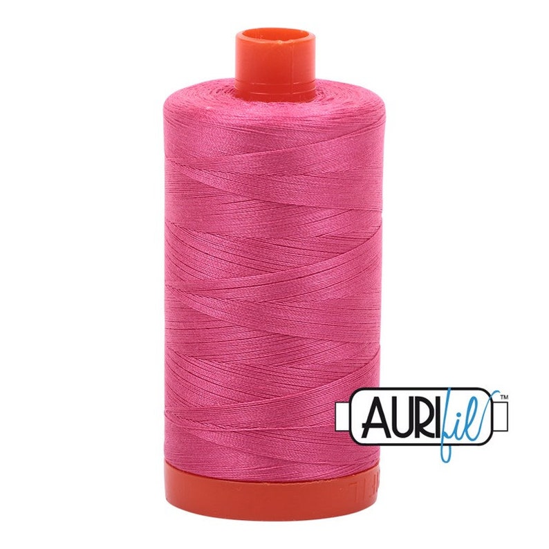 May include: A spool of pink thread with an orange plastic bobbin and the text "Aurifil" on the label.