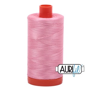 May include: A spool of pink Aurifil thread with a red plastic bobbin and a white label with the Aurifil logo.