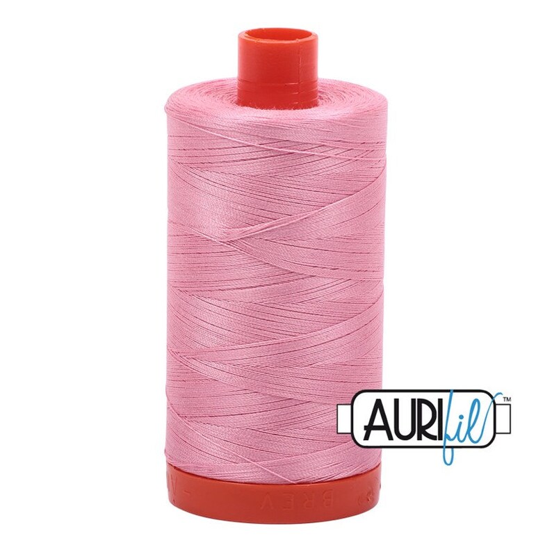 May include: A spool of pink Aurifil thread with a red plastic bobbin and a white label with the Aurifil logo.