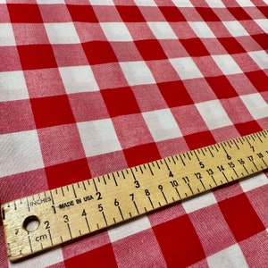 May include: Red and white checkered fabric with a wooden ruler measuring 18 inches. The ruler is marked in inches and centimeters.
