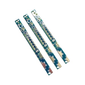 May include: Three green circuit boards with silver-coloured components and a zig-zag pattern.