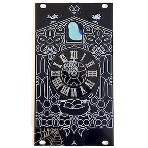May include: Black and white cuckoo clock with a blue bird on top. The clock face has Roman numerals and a stylized flower design. The clock is surrounded by intricate floral patterns.